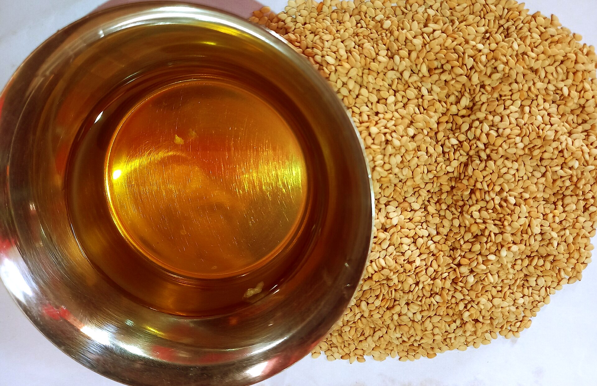 Golden, freshly pressed oil beside sesame seeds